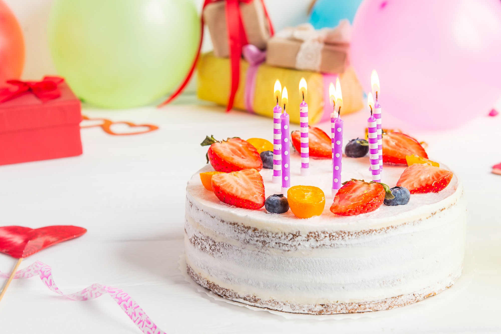 birthday-healthy-yogurt-berry-cake-with-candles-on-colorful-party-background-with-bright-party-tool.jpg